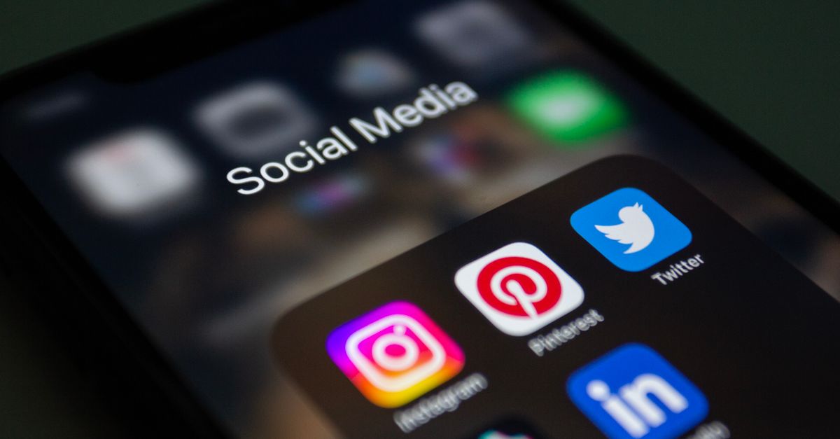 Main tenant un smartphone affichant du contenu vidéo sur une application de réseau social