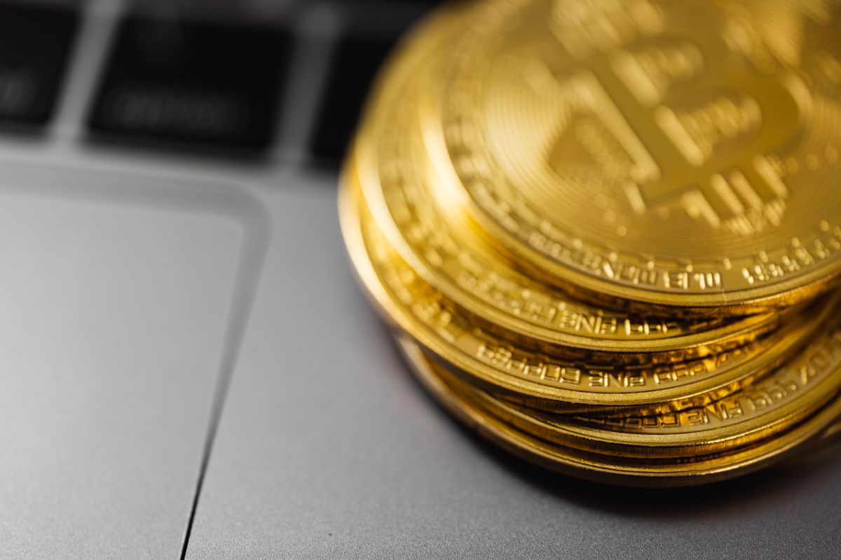 Piles de pièces de bitcoin doré posées sur un clavier d'ordinateur portable