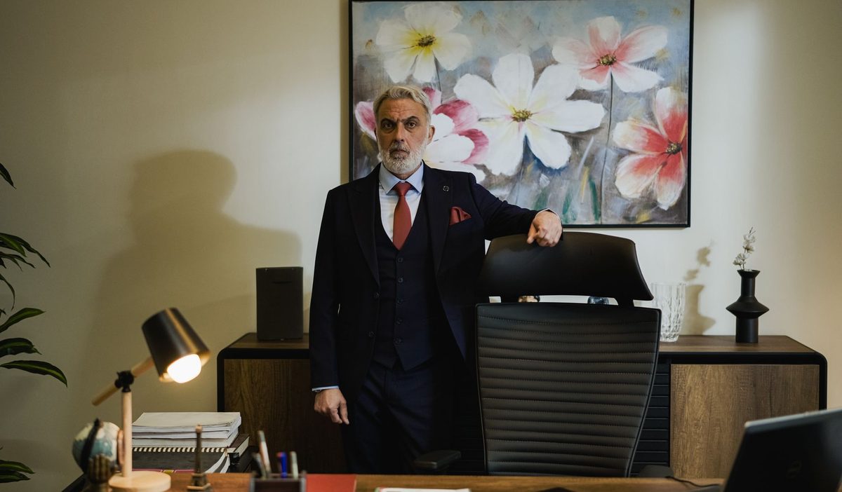 Dirigeant d'âge mûr debout dans son bureau, la main posée sur son fauteuil