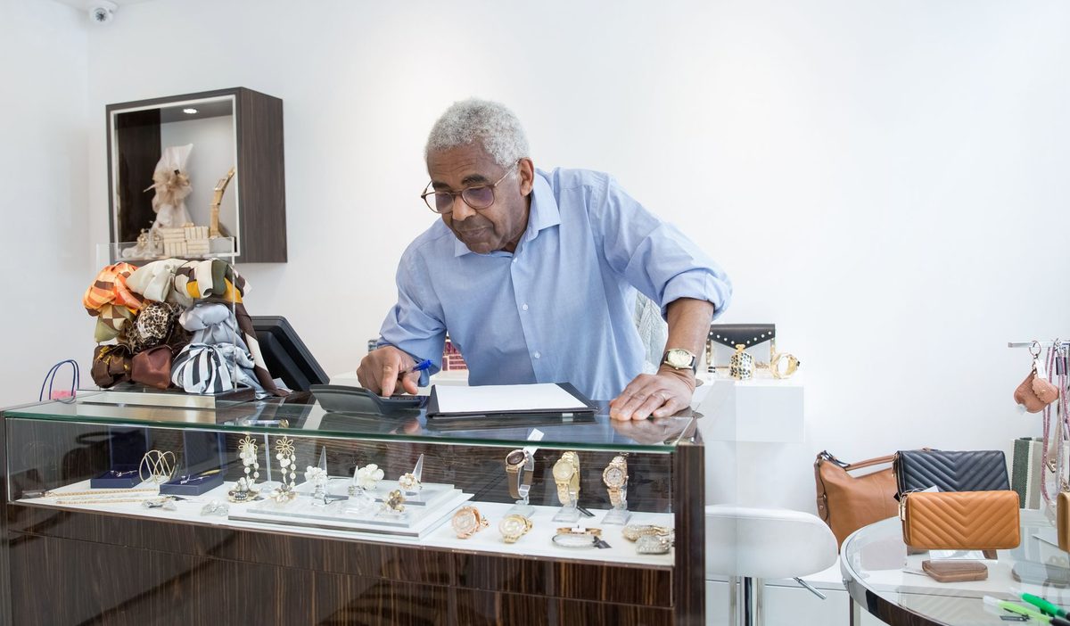 Commerçant d'âge mûr derrière le comptoir de sa boutique, consultant un document