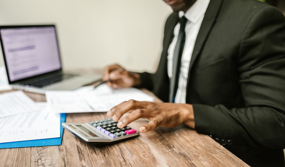 Dirigeant en costume calculant des montants sur des relevés bancaires à son bureau