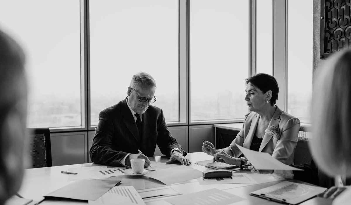 Deux associés en discussion autour d'une table de réunion, documents ouverts devant eux