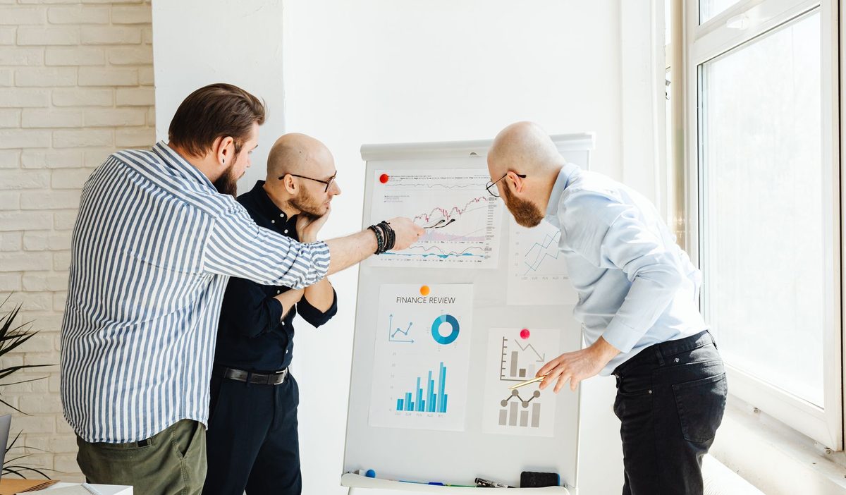 Trois collaborateurs analysant des courbes de ventes sur un paperboard